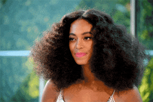Celebrity gif. Solange Knowles shakes her head to proudly move her natural, black curly hair.