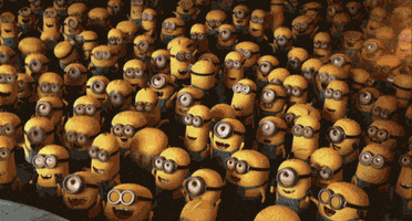 Despicable Me gif. A huge crowd of minions cheers enthusiastically, dancing together, jumping up and down, raising their arms, as a spot light pans over them. 
