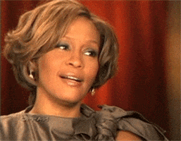 Celebrity gif. Whitney Houston on the Oprah show. She points at someone and smiles as if in agreement before dropping her hand and looking away, with her expression turning extremely indifferent and unimpressed. 