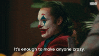 Movie gif. Joaquin Phoenix as the Joker in Joker turns toward us with disdain and says, "It's enough to make anyone crazy."