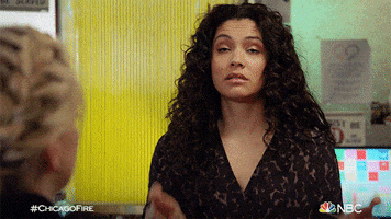 TV gif. Miranda Rae Mayo as Stella Kidd on Chicago Fire crosses her fingers on both hands.