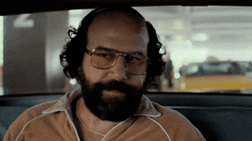 TV gif. Brett Gelman as Murray in Stranger Things. He's in a taxi and is clearly in a rush. He sharply glances at the driver and yells, "Let's go, this is life or death. Snap, snap." 