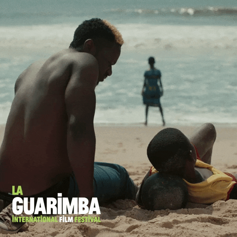 Ad gif. A scene from a movie advertising the La Guarimba Film Festival. A man and a boy are on the beach and the man tries to get the boy's attention by patting his shoulder. The boy throws his hand off and continues to ignore him.