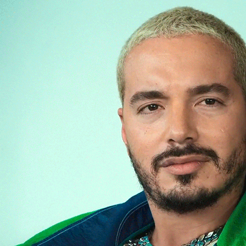 Movie gif. J Balvin lowers his head against his hands as he prays.