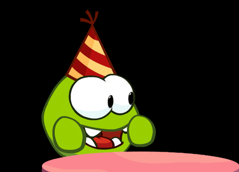 Kreslený pohyblivý obrázek se zelenou postavičkou s narozeninovou čepičkou jásající nad mrkvovým dortíkem s hořící svíčkou.