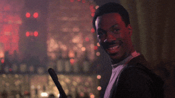 Movie gif. Eddie Murphy as Axel Foley in Beverly Hills Cop 4 makes an "OK" sign with his hand, the camera zooming in and freeze framing, before zooming out in front of shelf of wine bottles.