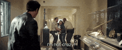 Movie gif. John Bradley as K.C. Houseman in Moonfall. He's being dragged away by two security guards as he yells, "I'm not crazy!" and throws the papers he's holding up into the air.