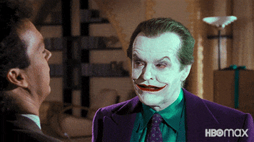 Movie gif. Jack Nicholson as the Joker in Batman looks around with narrowed eyes as Michael Keaton as Bruce Wayne speaks.