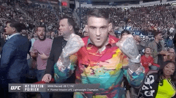 Sports gif. Dustin Poirier is hyped up in the crowd at a UFC fight. He brandishes his arms and flexes while roaring, "Let's go!" 