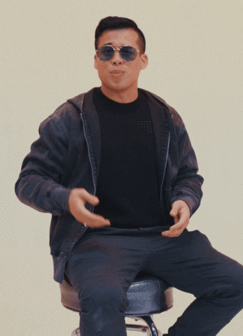 Video gif. Man wearing aviator sunglasses is sitting on a chair and looking expectantly at us. He raises one hand and then the other, in a this or that manner.