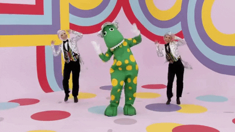 Pohyblivý gif k svátku s tancujícími lidmi a člověkem v obleku dinosaura na barevném pozadí.