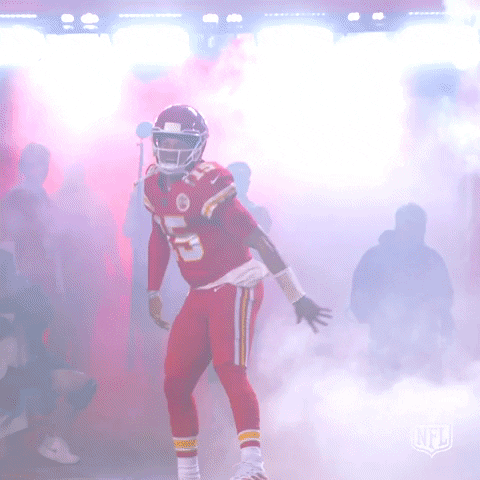 Sports gif. Patrick Mahomes of the Kansas City Chiefs celebrates as fog explodes around him and red lights fill the arena. He jumps up and down and roars with excitement, fist pumping at the crowd.