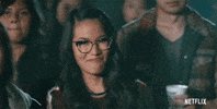 Movie gif. Ali Wong as Sasha Tran in Always Be My Maybe stands among an audience while pointing and smiling in an affirmative way.