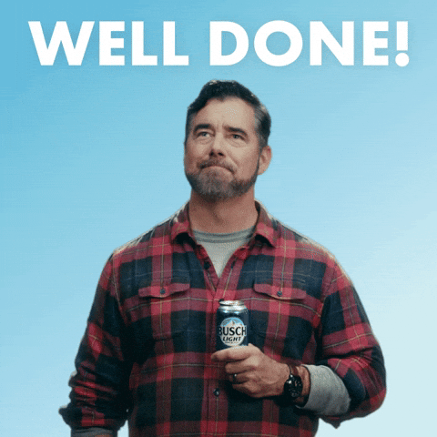 Sponsored gif. Gerald Downey in a red and black plaid shirt looks out into the distance with a proud expression, gesturing with a salute while holding a can of Busch Light beer at his chest. Text, "Well done!"
