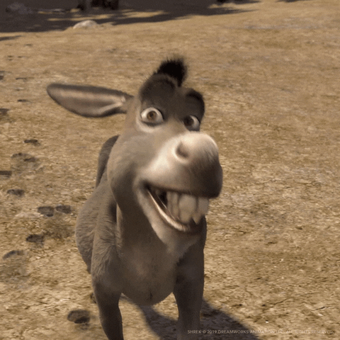 Movie gif. Donkey from the movie, "Shrek" stands in a dirt field and looks at us, batting his eyelashes and cocking his head to one side, giving us a sweet toothy smile. 