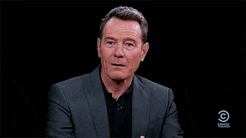 Celebrity gif. With a slight smile Bryan Cranston points to himself in shock and mouths the word "me."