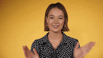 Video gif. Smiling model claps her hands with excitement against a yellow background.