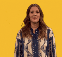 Video gif. Against a solid yellow background, Drew Barrymore puts her hands to her chest in gratitude, and tilts her head as she says: Text, "Thank you." Then, a white illustrated heart rises from bottom of frame.