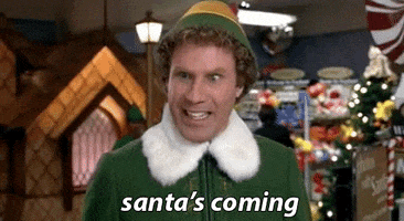 Movie gif. Will Ferrell as Buddy the Elf is in the department store’s children’s section that’s decorated for christmas. He tries to control his complete and utter excitement when he says. “Santa’s coming.”