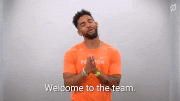 Celebrity gif. Wearing an orange "Peloton" shirt, Rad Lopez puts his hands together in gratitude and gives us a cheerful welcome. Text, "Welcome to the team. So happy to have you here."