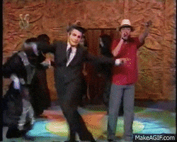 Celebrity gif. Don Francisco comes waltzing out into the spotlight with a group of masked background dancers. He wears a sombrero hat as he theatrically dances in front of an admiring crowd waving banners of pink cloth.