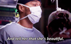 TV gif. Jesse Williams as Jackson Avery on Grey’s Anatomy wears surgical scrubs and a mask and looks over at someone, saying, “And tell her that she’s beautiful.”