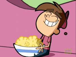 Cartoon gif. Timmy on the Fairly Oddparents sits on a pink couch with a huge bowl of popcorn and joyfully plunges his head into the bowl as popcorn flies up.