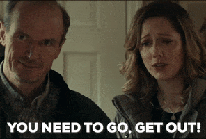 Movie gif. Judy Greer as Karen Nelson in Halloween stands next to her husband at the front door. Shutting the door with a worried look on her face, she says, "You need to go, get out," which also appears as text.