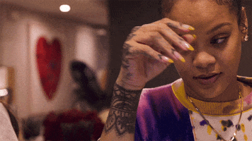 Celebrity gif. Rihanna looks frustrated as she looks down into the distance. Her hand is dangling in the air as she leans on her elbow and she slowly brings her hand down as well.
