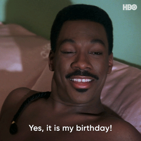 Movie gif. Clip shows a young, shirtless Eddie Murphy in character lounging in bed as he lifts his head, smiles wide and nods as he says, "Yes, it is my birthday!'