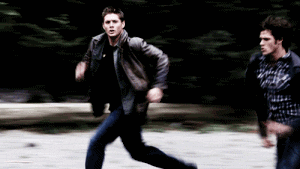 TV gif. Jensen Ackles as Dean in Supernatural runs fast along with Jared Padalecki as Sam, fleeing something. Text following Sam reads, "Run bitch run."