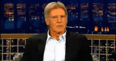 Celebrity gif. Harrison Ford as a talk show guest looks off to the side, confused, and then leans forward and sneers, "Who gives a shit?" which appears as text.