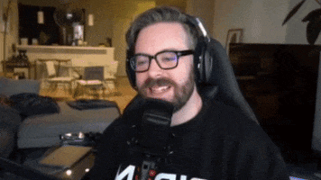 Celebrity gif. Greg Miller wears headphones as he sits in front of a microphone in his living room. He holds up a finger and laughs as he says: Text, "That's bait."