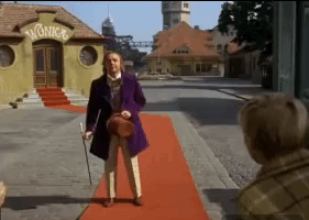 Movie gif. Gene Wilder as Willy Wonka in Willy Wonka and the Chocolate Factory stands stiffly, knees locked, staring blankly, then falls stiff like a board forward toward the ground in unconscious peril, but recovers at the last possible second, tucking a somersault and rolling up on to his feet with a smile and an agile magician's flourish.