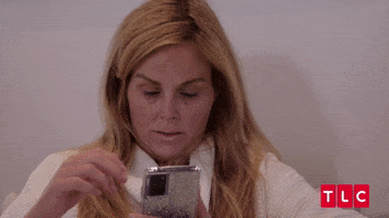 Reality TV gif. Stephanie from TLC's 90 Day Fiancé sits barefaced in a bathrobe and wearily scrolls through her phone before doing a doubletake and reacting to something with exasperated shock and annoyance.