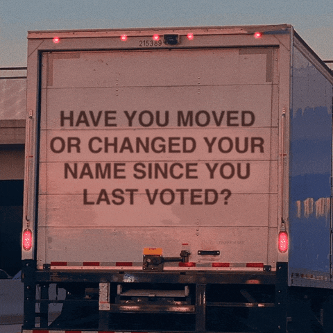Video gif. Close-up of the back of a white moving truck with its hazard lights blinking. Text on the back of the truck reads, “Have you moved or changed your name since you last voted?”