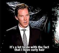 A white man in a suit sits and talks to someone