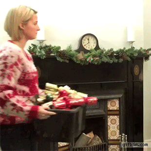 Video gif. Woman comes out carrying a box full of Christmas tree decor. She frowns at the box and the naked Christmas tree and she tosses the whole box on the tree. Magically, the tree gets decorated and she nods with success.