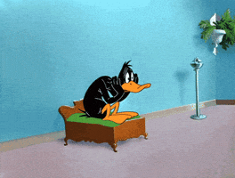 Cartoon gif. A worried Daffy Duck sits on a tiny bed, gently slapping his cheeks.