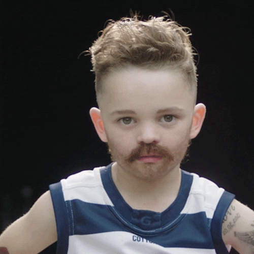 Video gif. A young child wearing fake tattoos and a mustache winks at the camera.