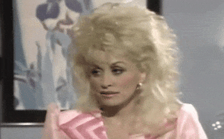 Celebrity gif. Dolly Parton tilts her head to the side, blinking as if unimpressed.