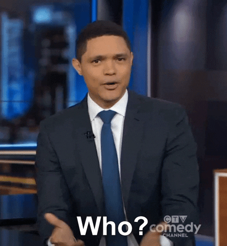 TV gif. Trevor Noah on The Daily Show sits at his desk, shaking his head in disbelief and says, “who?” He gives a small shrug and stares at us for answers. 