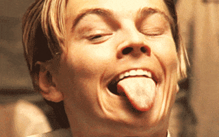 Video gif. A young Leonardo DiCaprio pulls his lips back and sticks out a pointy tongue with narrowed eyes. 