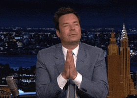 Tonight Show gif. Jimmy Fallon on the Tonight Show has his eyes closed and his hands are in prayer position as he looks both grateful and hopeful. He kisses his hands and sends it out to us.