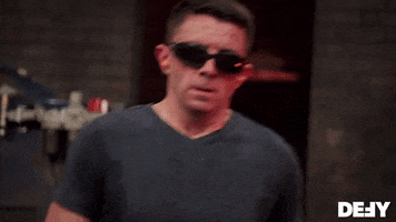 Reality TV gif. Ben Abbott from Forged in Fire walks away from the fire and blows air out of his mouth. He still has safety googles on and sweat coats his t shirt, showing the amount of effort has gone into his ware.