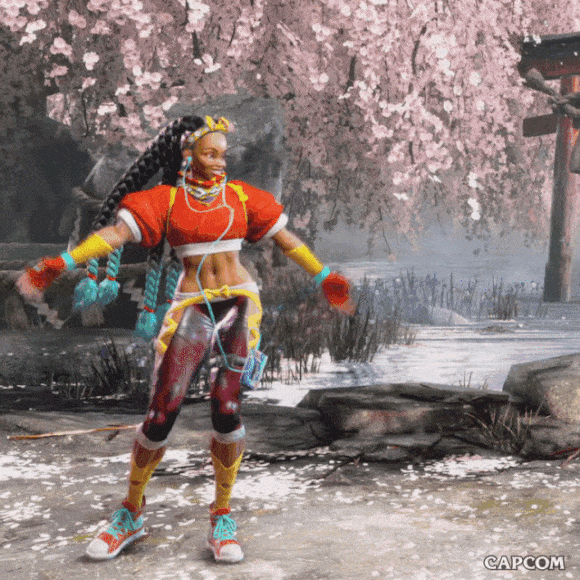 Video game gif. Kimberly in "Street Fighter VI" swoops her arms out and around to a prayer pose, then dips down and does a spin move, posing with her back to us, thumbs pointing inward towards her face in a cute, sassy pose. The background is a Japanese garden with a cherry tree, sending pink blossoms through the air. 