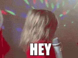 Video gif. A young blonde girl in a red sweater, holding a microphone, whips around to face us, flipping her hair and saying, "Hey."