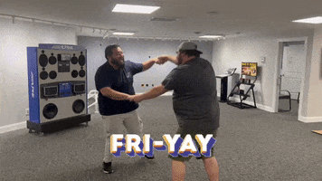 Video gif. Two men in an office hold hands and spin around together, ecstatic. They separate and one man runs towards us, jumping. Text, "It's Fri-yay!"