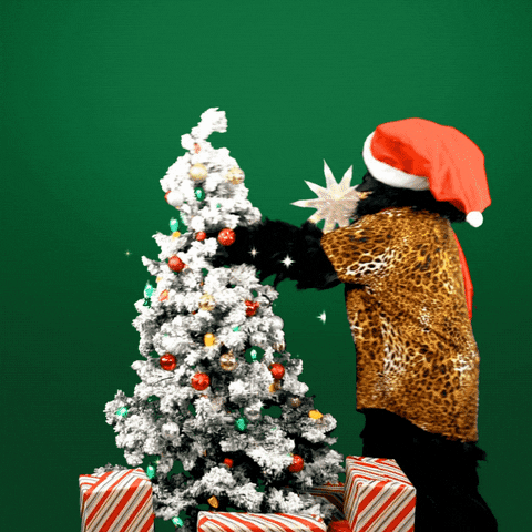Video gif. Person dressed in a gorilla costume wearing a cheetah-print shirt and Santa hat attempts to put a star on top of a Christmas tree, then falls forward over it, crashing to the ground in a cloud of white flocking snow. The scene changes to gleaming letters on a holly green background, "Merry Christmas and Happy New Year."