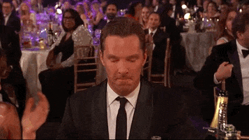 Celebrity gif. At an award show, Benedict Cumberbatch raises his glass and bows his head with gratitude.